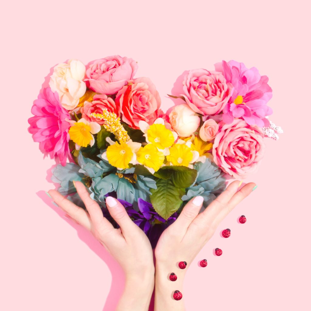 Blumenstrauß in Form eines Herzens der von zwei Händen gehalten wird