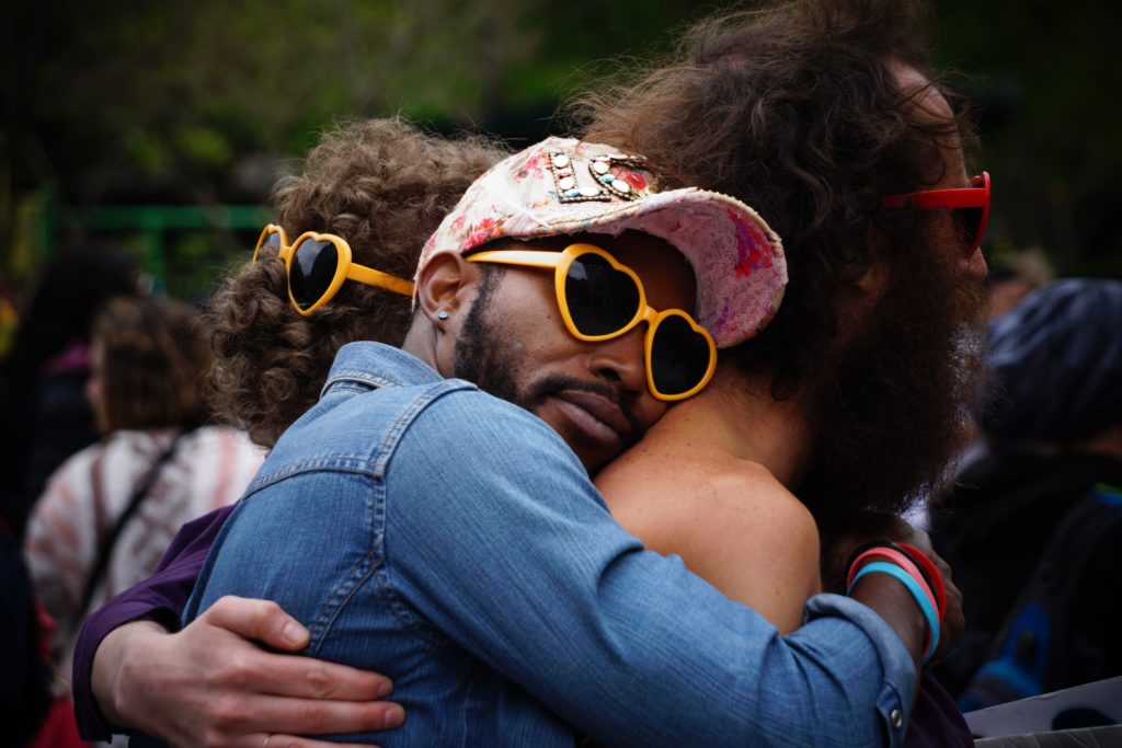 Drei Menschen die Sonnenbrillen in Herzform tragen und sich umarmen