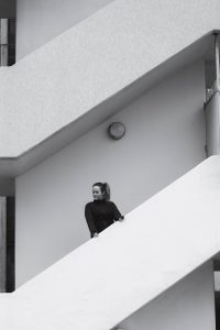 Bild in schwarz-weiß. Jen steht auf einer Treppe im Running Outfit von Adidas