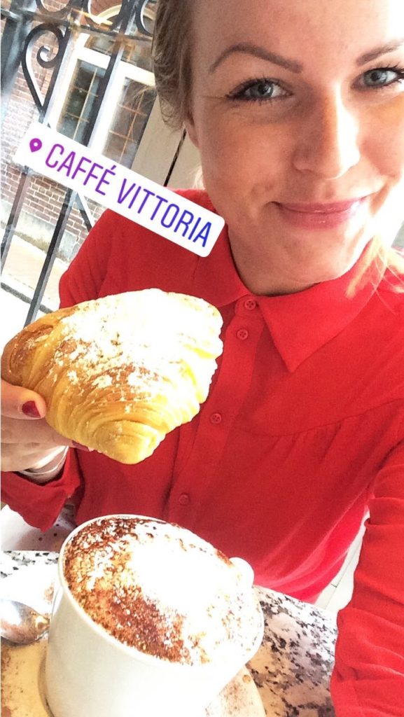 Reisebericht Boston. Editorin Hannah mit einem Croissant und einem Kaffee.