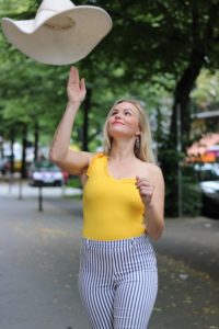 Sommer Outfit mit dem Bumble x SWIM WITH MI Badeanzug.Hannah schmeißt den Hut in die Luft.