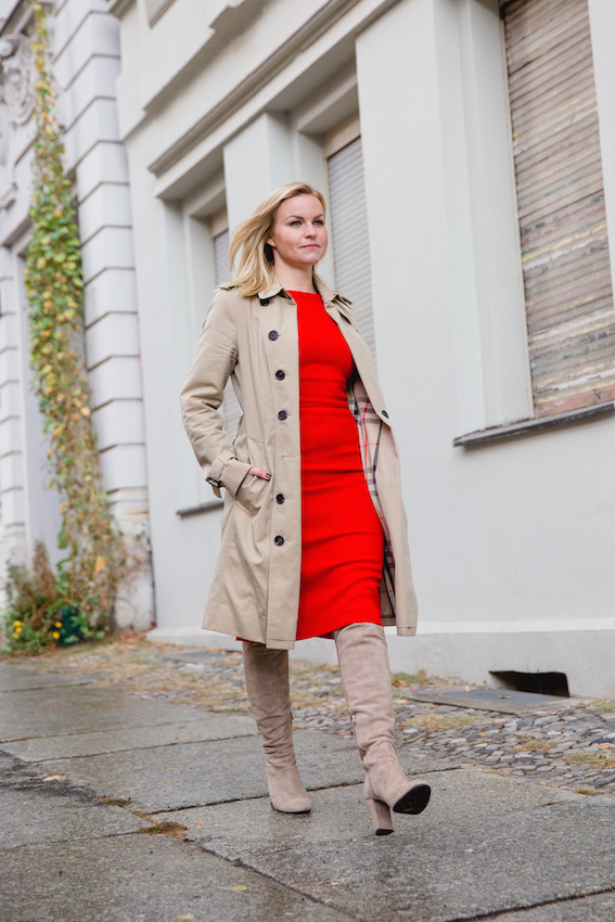 Business Frau Hannah trägt ein rotes Kleid des nachhaltigen Modelabels J.Jackman mit einem Mantel von Burberry und Overknee Stiefeln