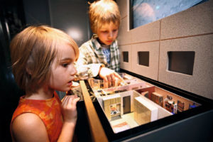 Kinder schauen sich ein nachgestelltes Wohnzimmer aus DDR Zeiten an