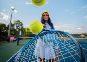 Frau mit Tennisschläger und hüpfenden Bällen